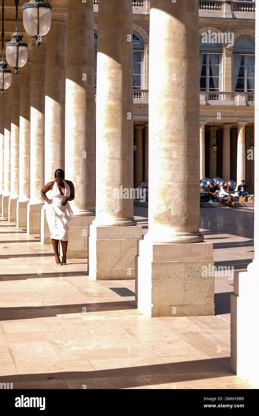 Young Black Woman Posing for Photos in a White Dress at the Columns of the Palais Royal in Paris, France - Fashion, Influencer Stock Photo