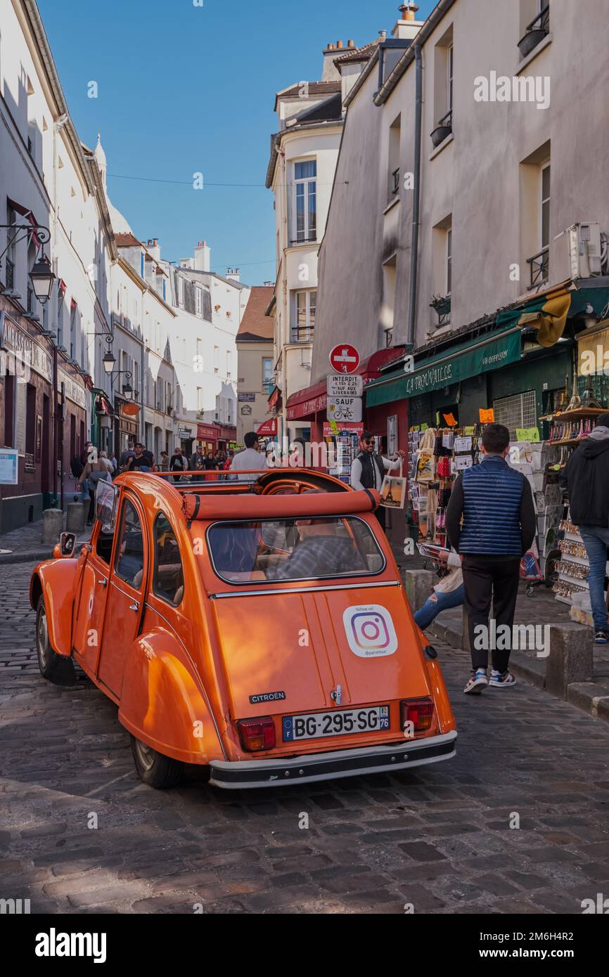 Picturesque Street in Montmartre with a Classic Orange Car Passing by - Paris, France Stock Photo