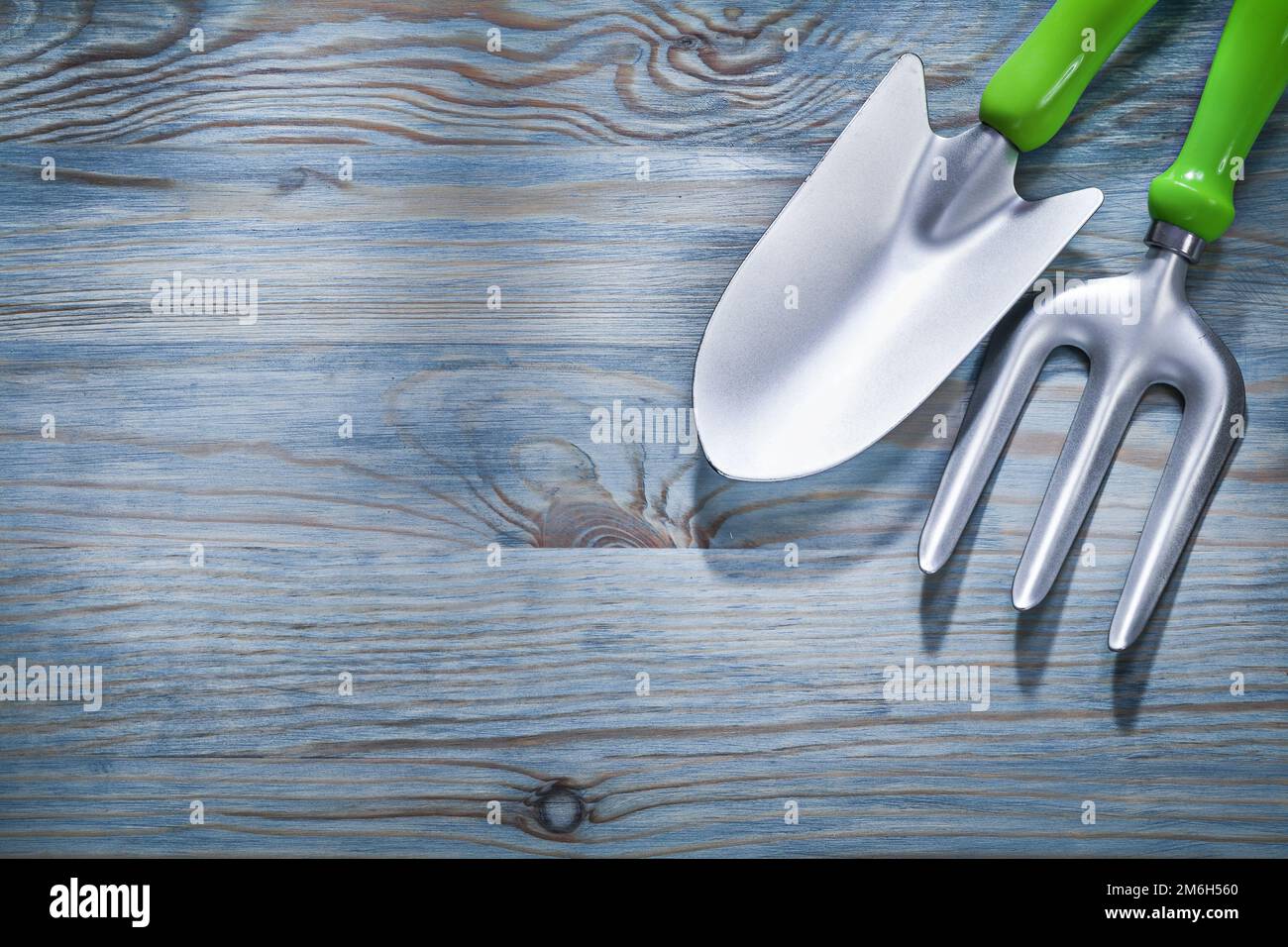 Hand spade trowel fork on wooden board gardening concept. Stock Photo