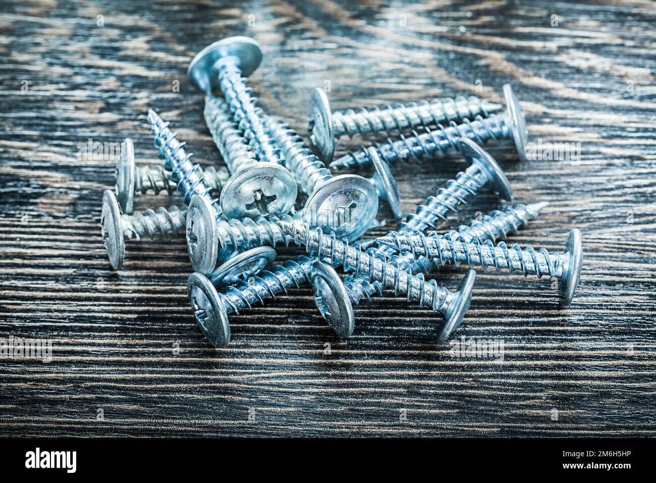 Heap of stainless screws on wooden board. Stock Photo