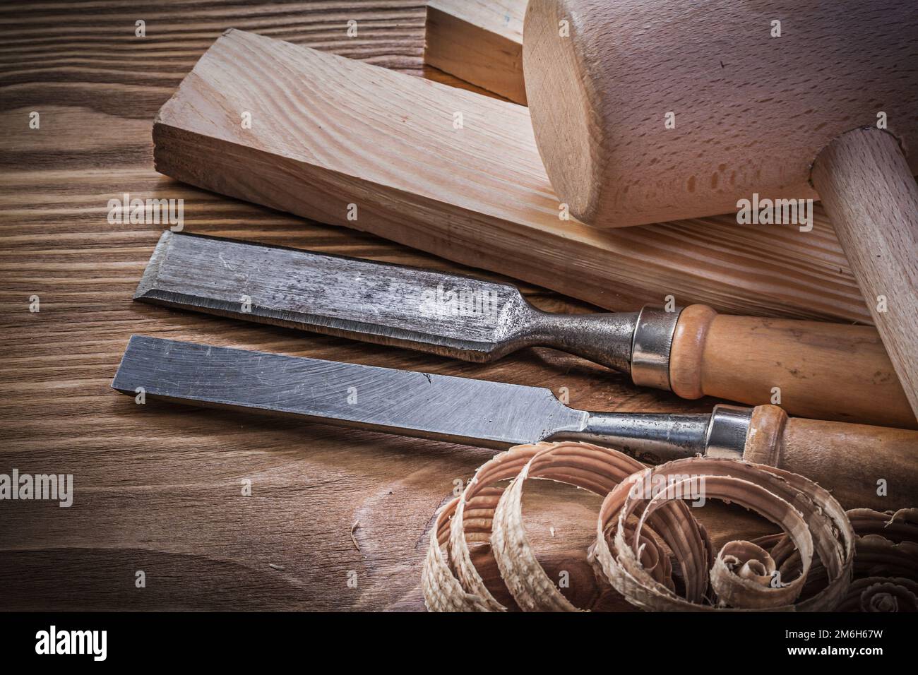 Lump hammer wooden stud firmer chisels planning chips on vintage wood board. Stock Photo