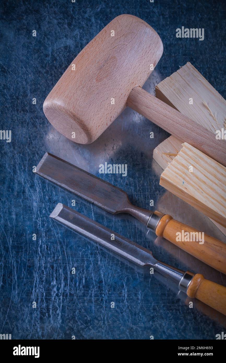 Lump hammer wooden studs and flat chisels on scratched metallic background close up view construction concept. Stock Photo