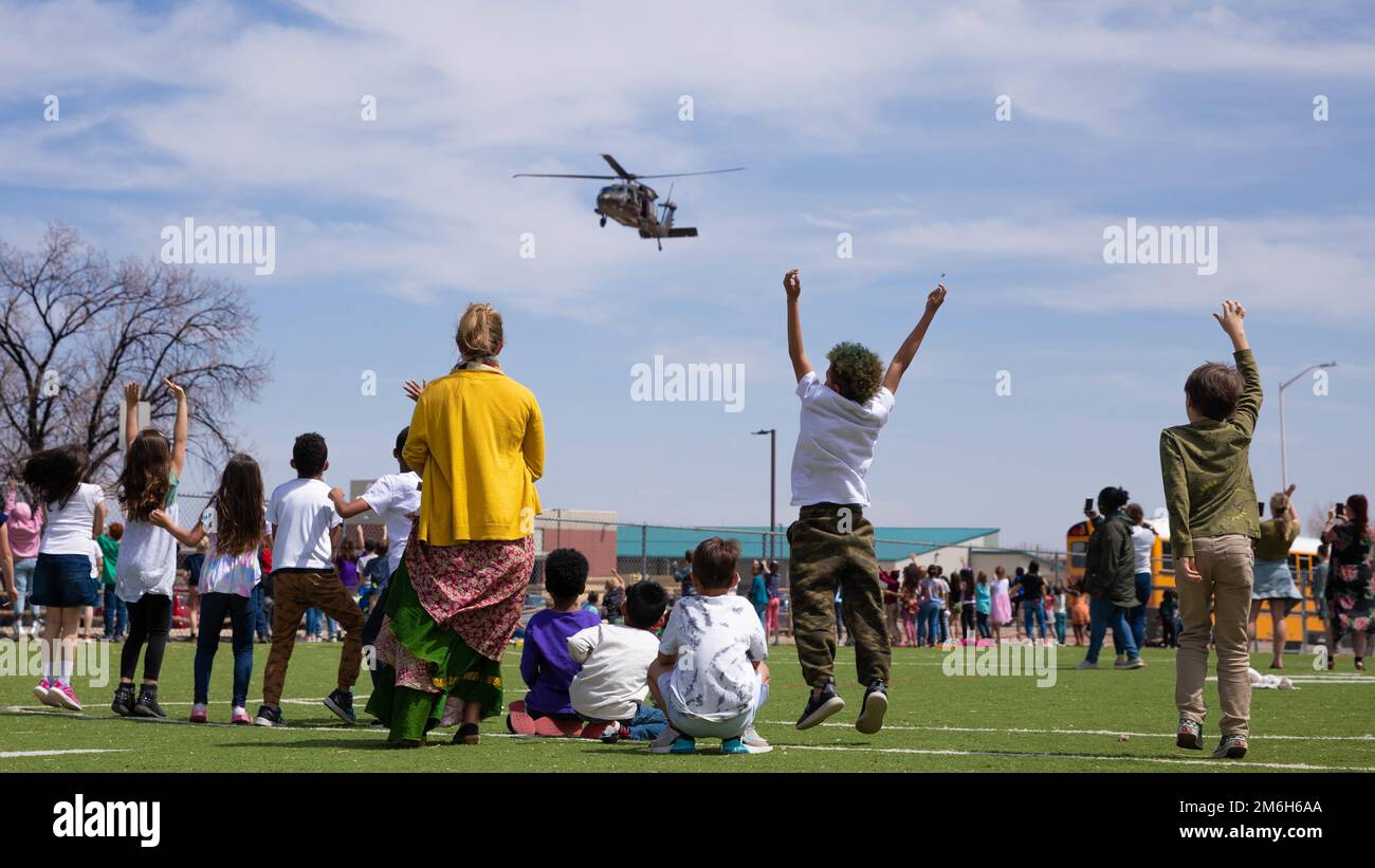 Elementary school students jump in the air as a UH60 Black Hawk flies over them for the Month