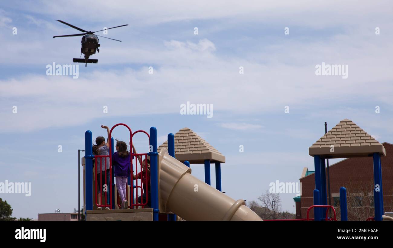 Elementary school students watch as a UH60 Black Hawk flies over them for the Month of the
