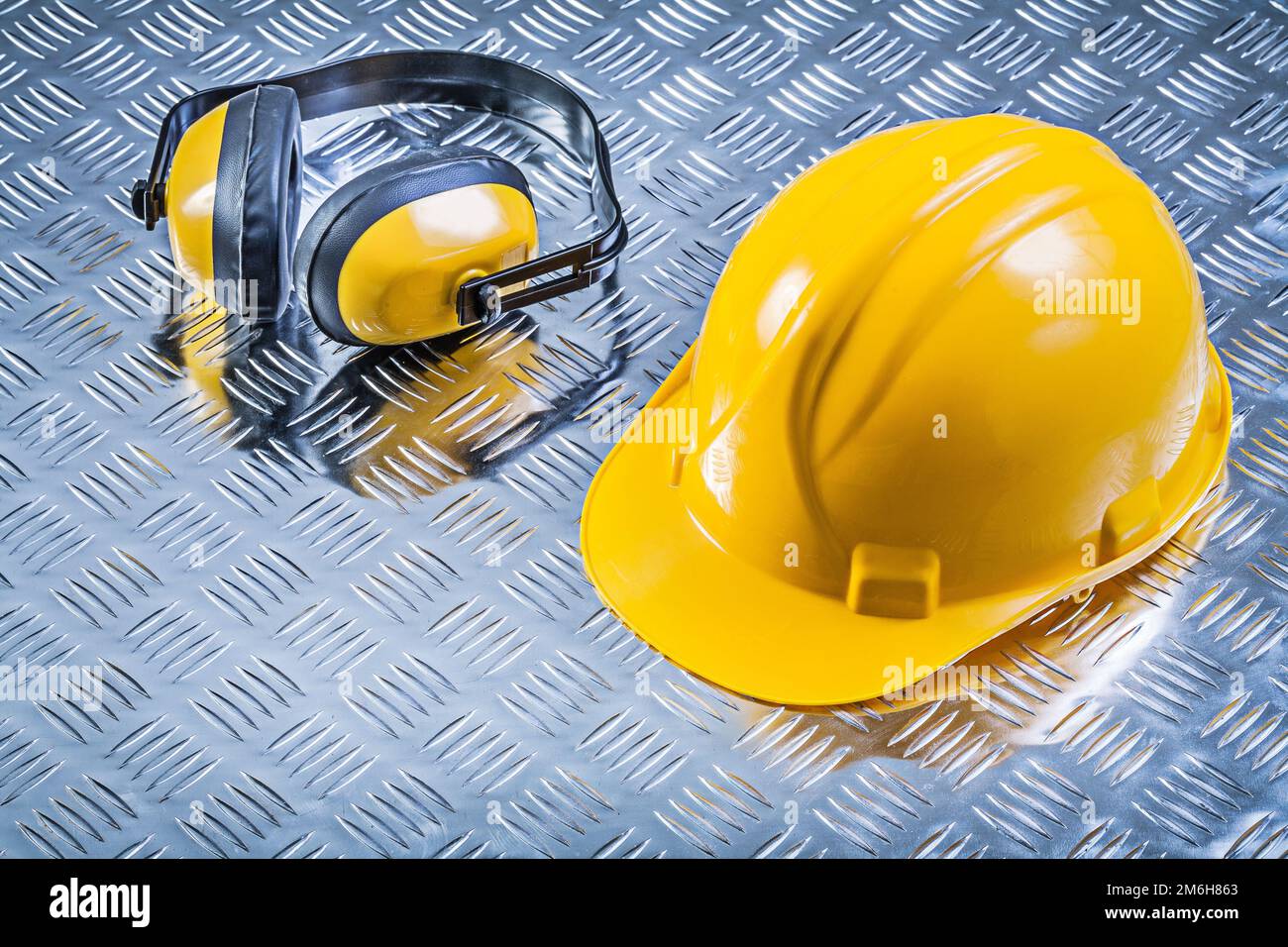 Protective ear muffs hard hat on fluted metal background construction