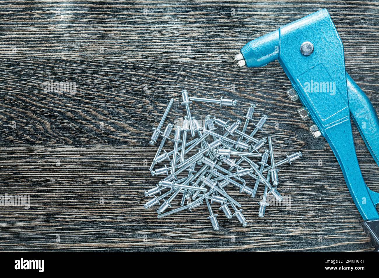 Riveting pliers stainless screws on wooden board. Stock Photo