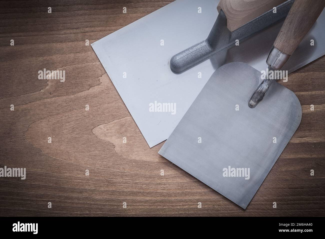 Stainless plastering and bricklaying trowels on wooden board