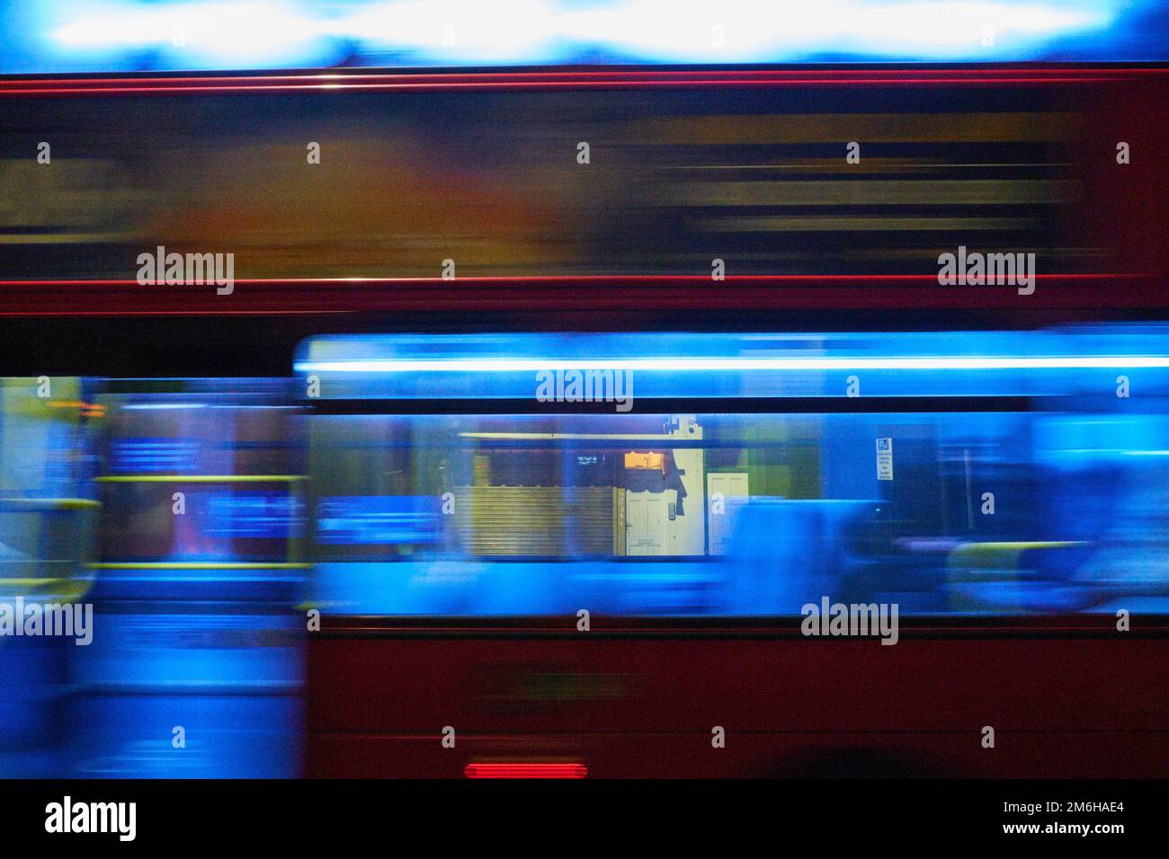 The brightly lit inside of a london bus pass by in a blur as the street beyond is seen through