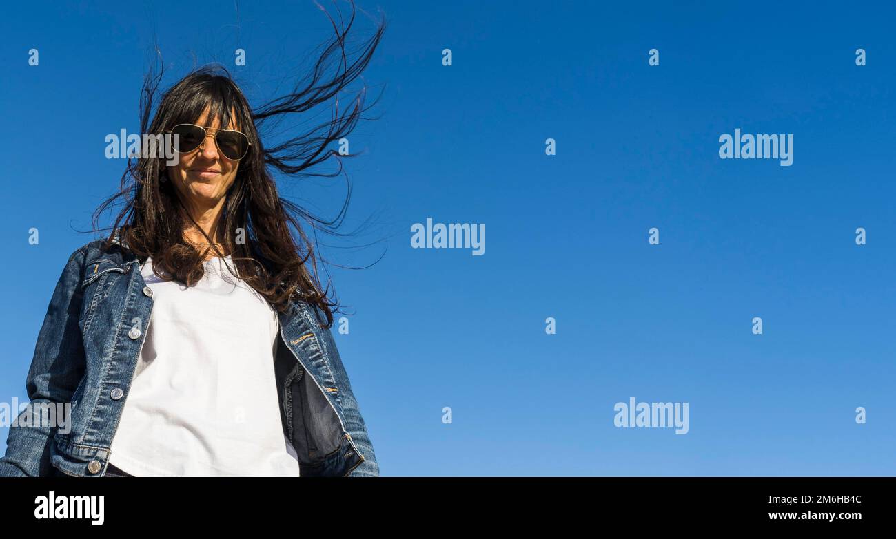 Low angle view of a similing woman outdoors. Blue sky background Stock Photo