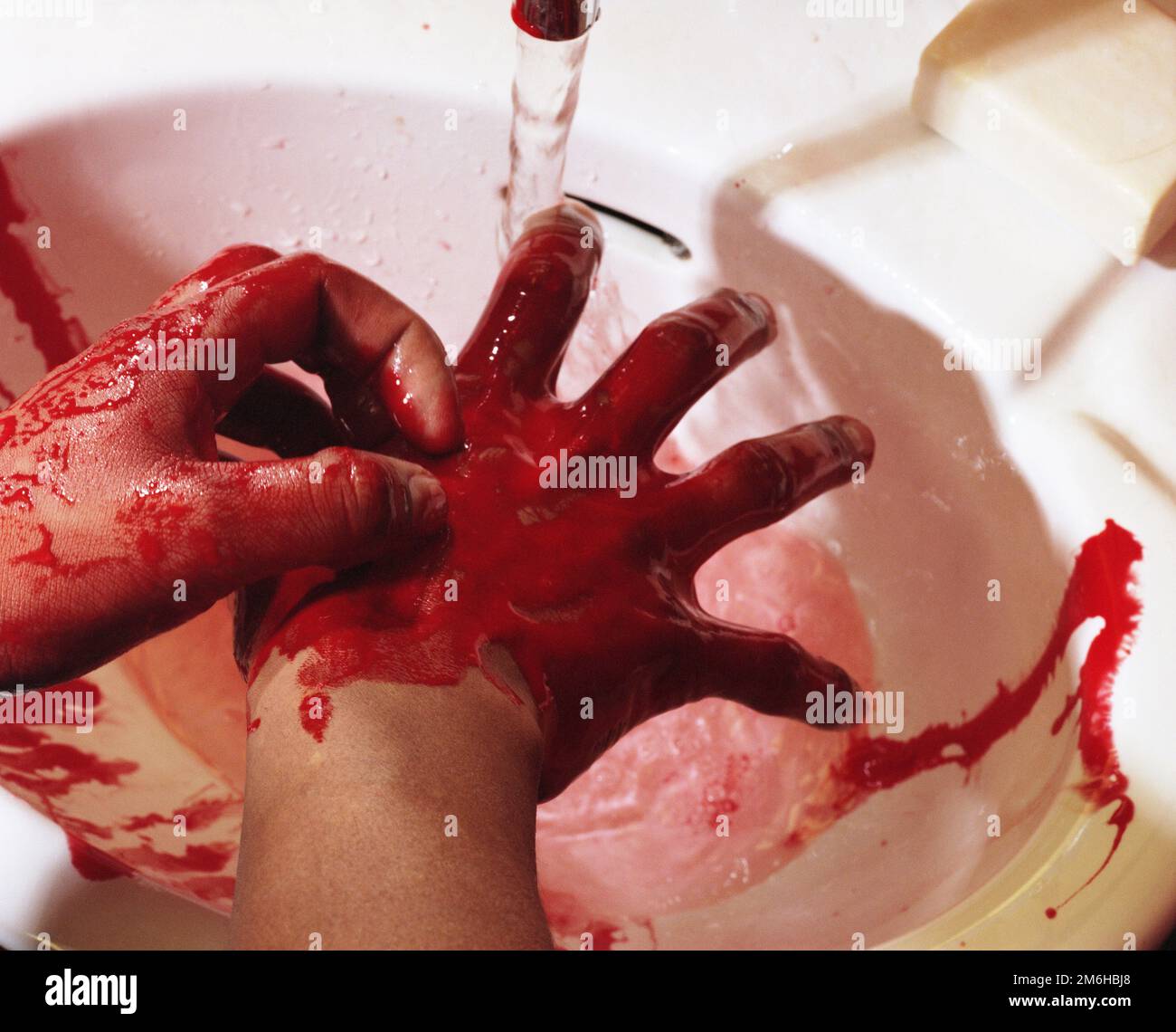 A man washing the blood from his hands with water in a sink basin. Image shot 2000. Exact date unknown. Stock Photo