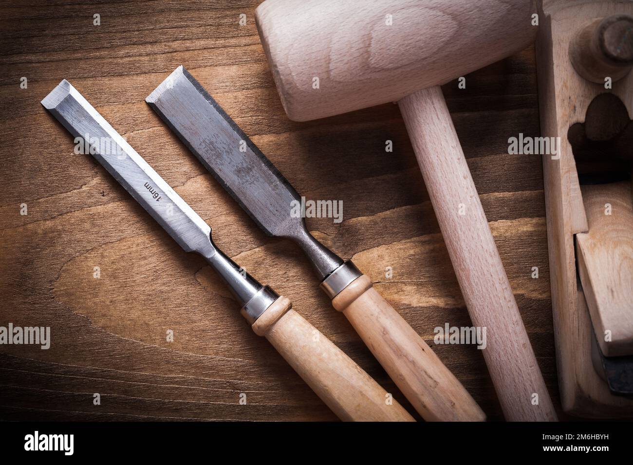 Wooden hammer shaving plane flat chisels on wood board top view construction concept. Stock Photo