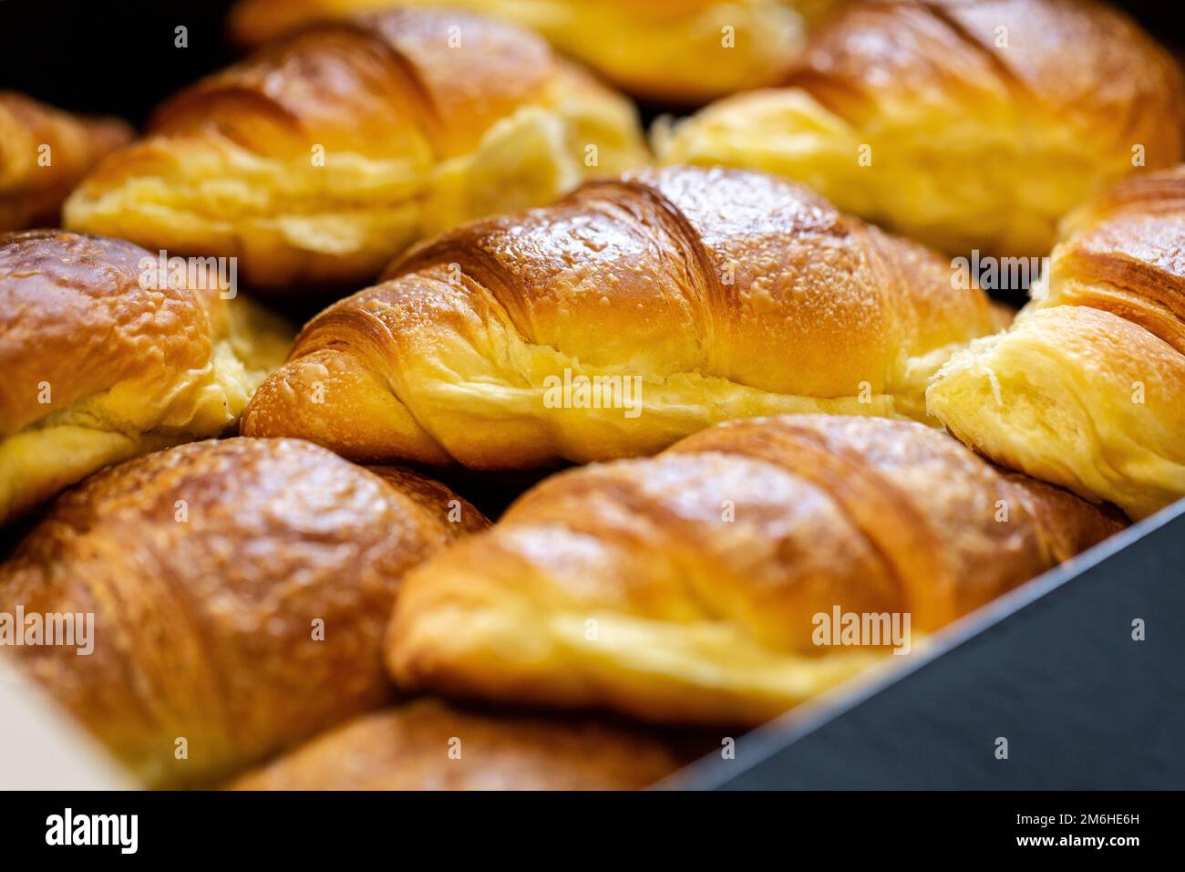 Selective focus on a croissant in a box full of pastries. Concept of breakfast or lunch break with packaged sweets, a delight for the palate but with Stock Photo