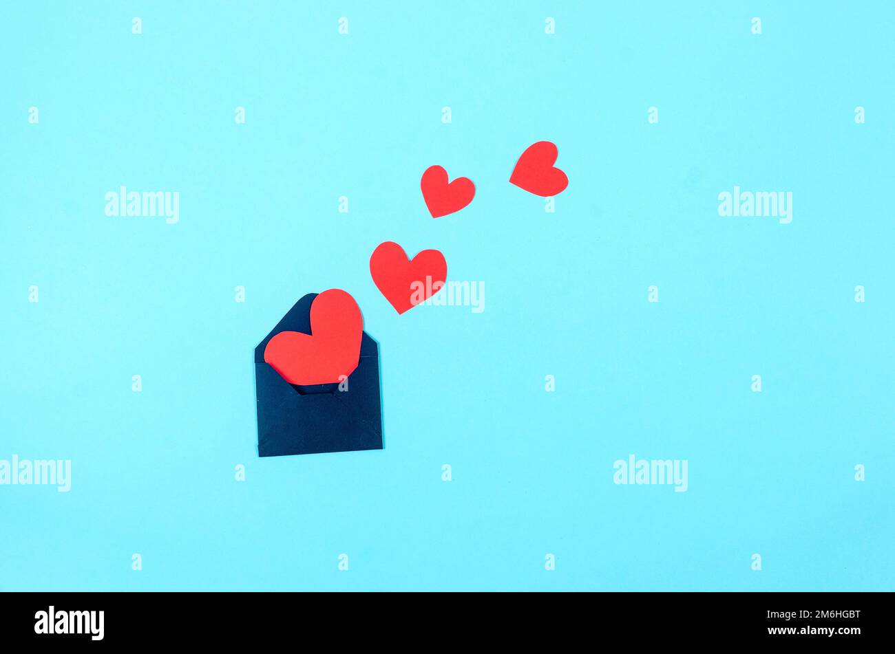 Red paper hearts in craft envelope on a blue background. Concept of the ...
