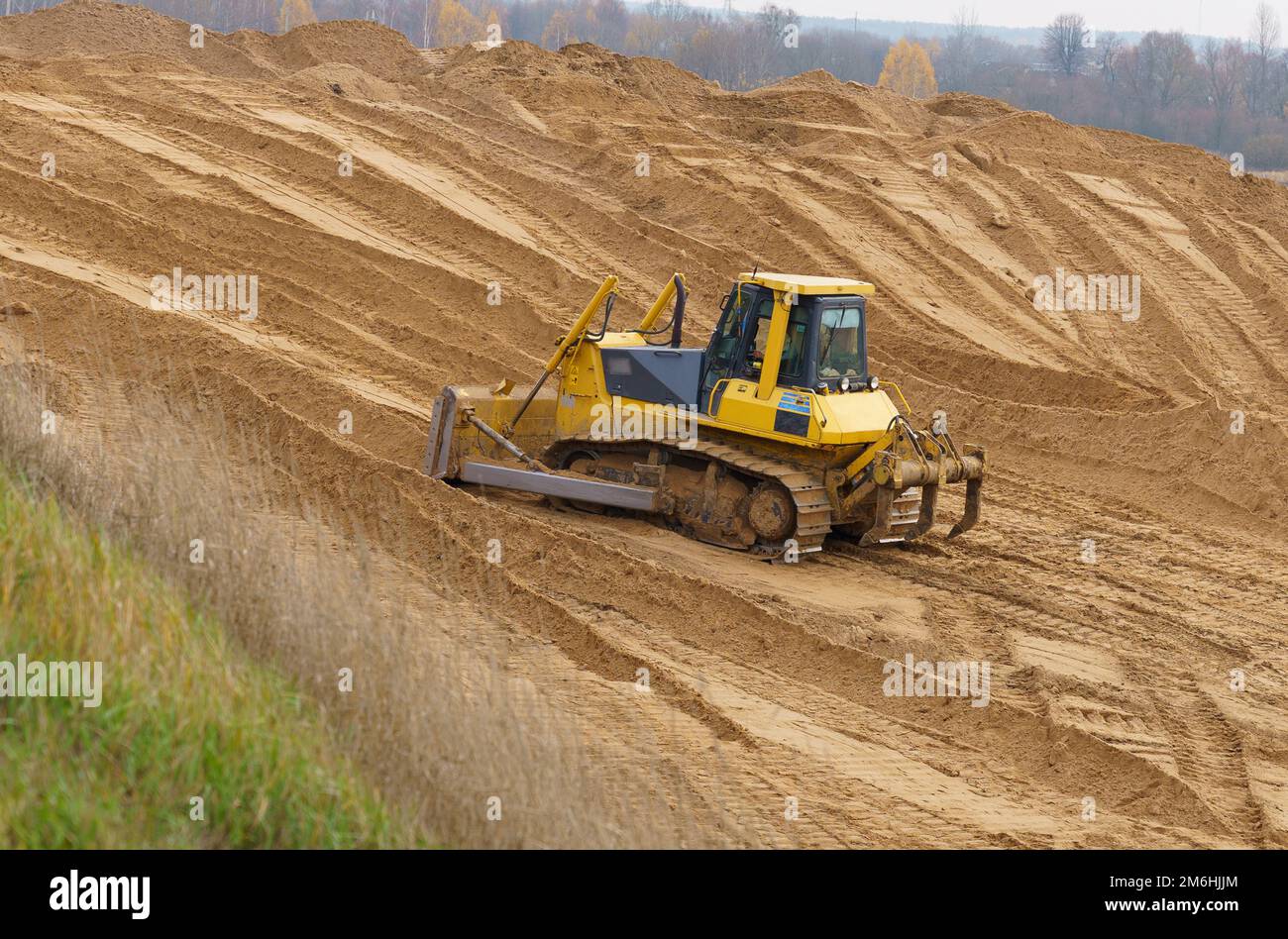 Bulldozer at the construction site of the bridge rakes sand Stock Photo