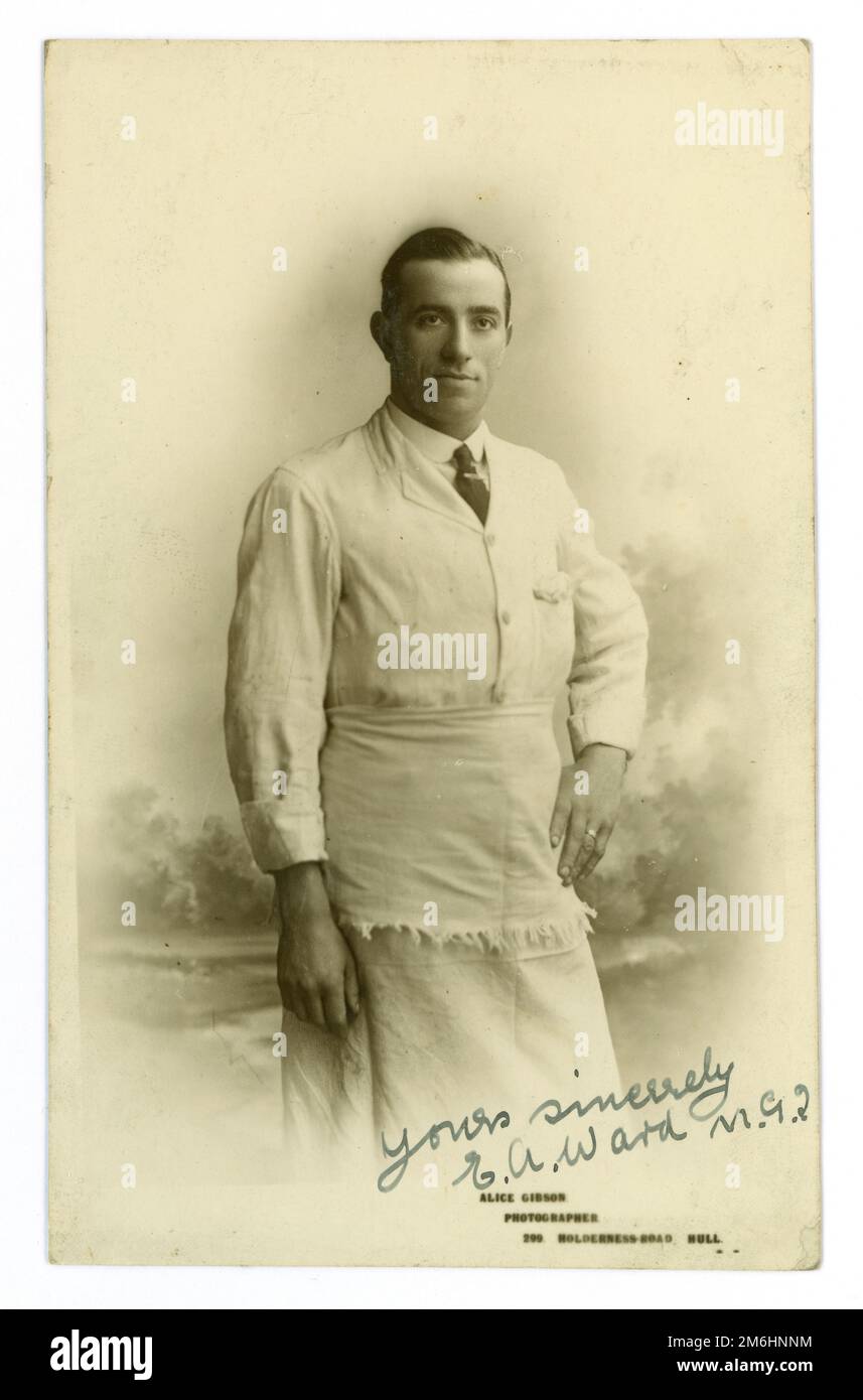 Original post WW1 era studio portrait postcard of a handsome grocery or dairy store assistant / proprietor,  wearing an apron, and shirt and tie. From the studio of  Alice (Maud) Gibson at 299 Holderness Road, Hull, Yorkshire, England, UK. Circa 1919. Stock Photo