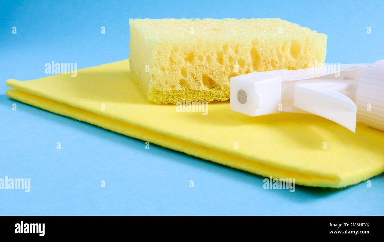 Set of cleaning products on a blue background. Yellow rag and sponge, cleaning spray, detergent. House cleaning concept. Stock Photo