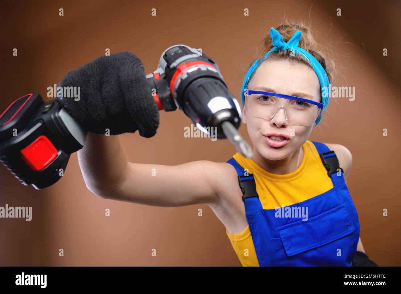 Studio portrait of a cocky caucasian young woman with a menacing grimace on her face. Threatens to repair with a screwdriver Stock Photo