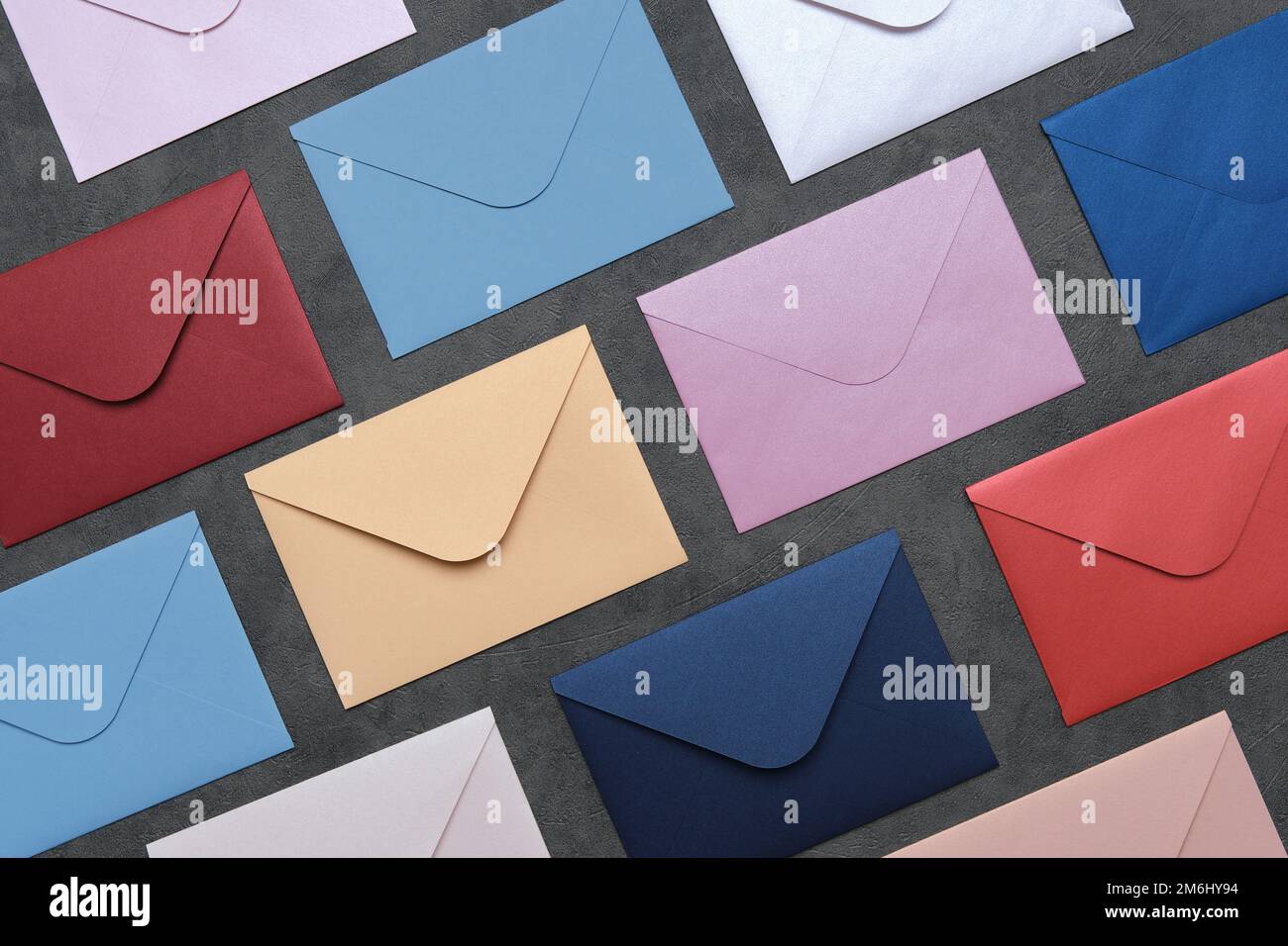 Rows of envelopes of different colors on gray background. Top view