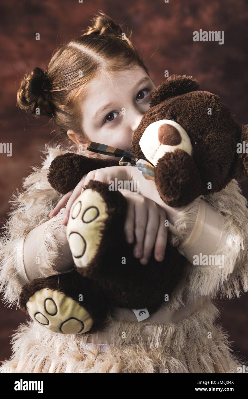 Portrait of a little red hair girl kissing her teddy bear Stock Photo