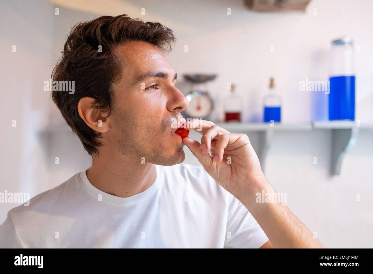 Young man eating a fresh cherry tomato Stock Photo