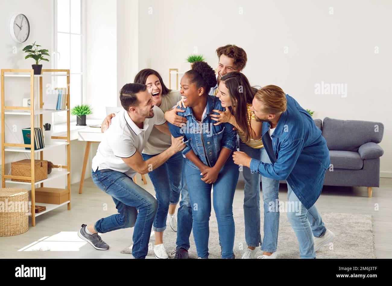 Happy young people laughing at a funny joke their friend has told at a party at home Stock Photo