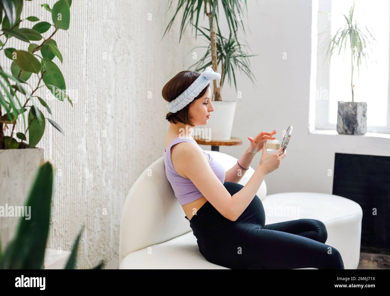 Pregnant young woman applying cream in morning Stock Photo