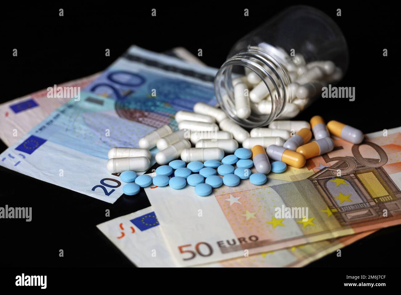 Pills on euro banknotes, medication in capsules scattered from the bottle. Concept of health