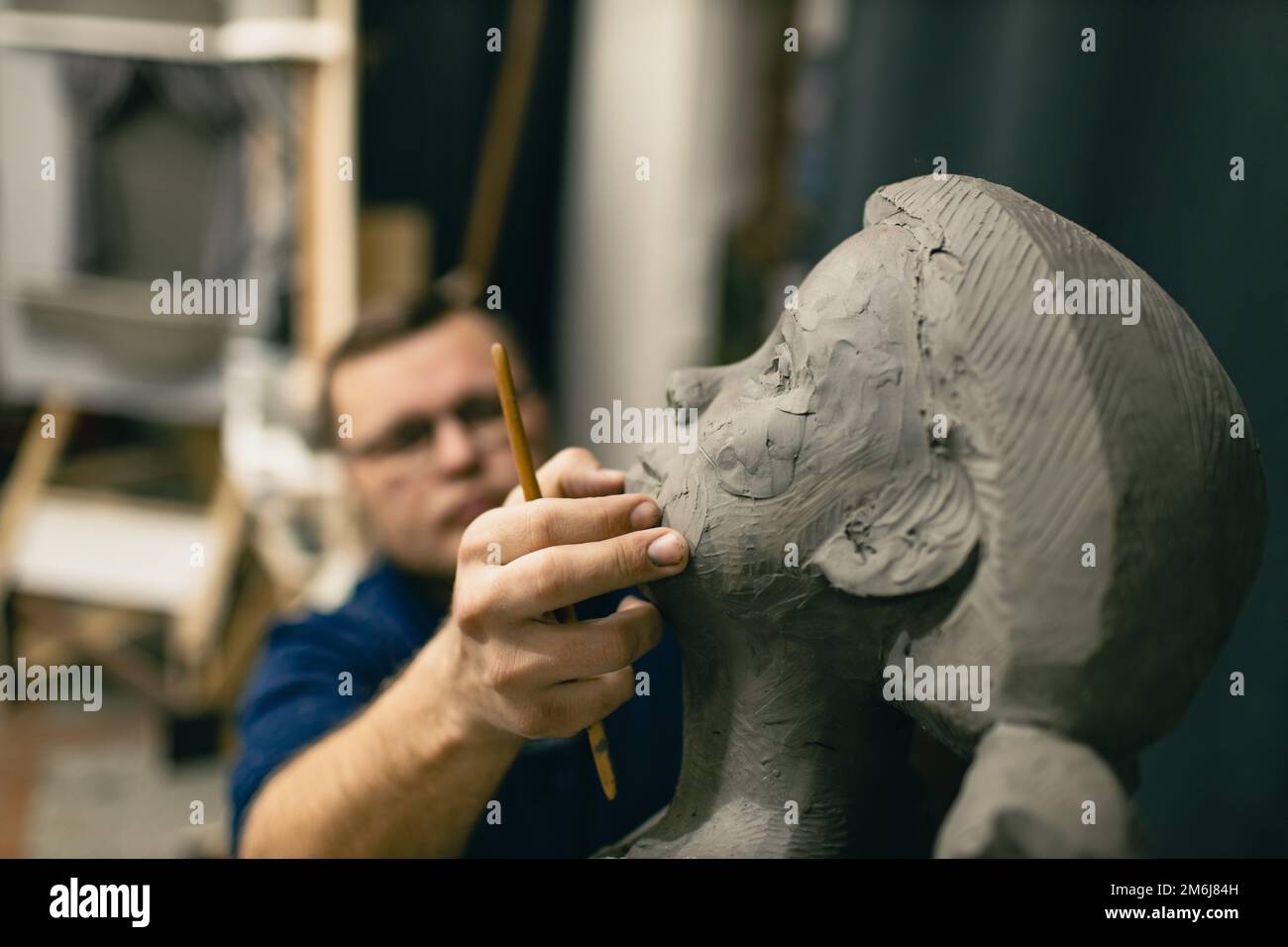 Man sculptor creates sculpt bust clay human woman sculpture. Statue