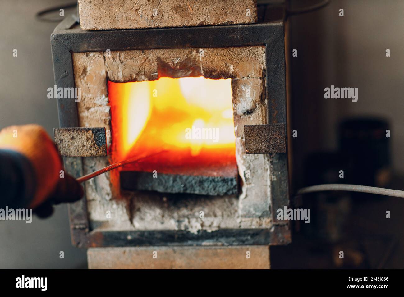 Blacksmith forge oven with hot flame. Smith heating iron piece of steel in fire of red-hot forge Stock Photo