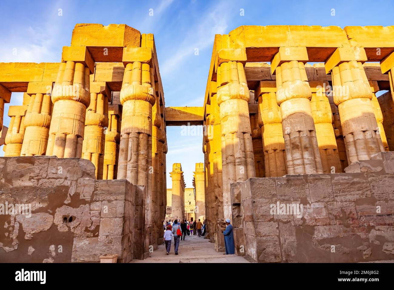 Unknown tourists walking through the columns of hypostyle hall of Pharaoh Amenhotep III in Luxor Temple Complex. Stock Photo