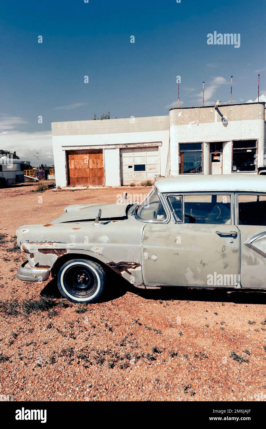 Old derelict rusted 1959 Ford Fairlane 500,4 door sedan, parked in front of an abandoned service station Stock Photo