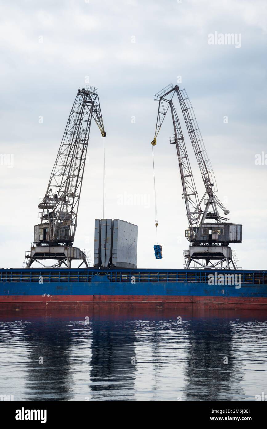 Cranes at cargo terminal in  docking station loading cargo ship Stock Photo