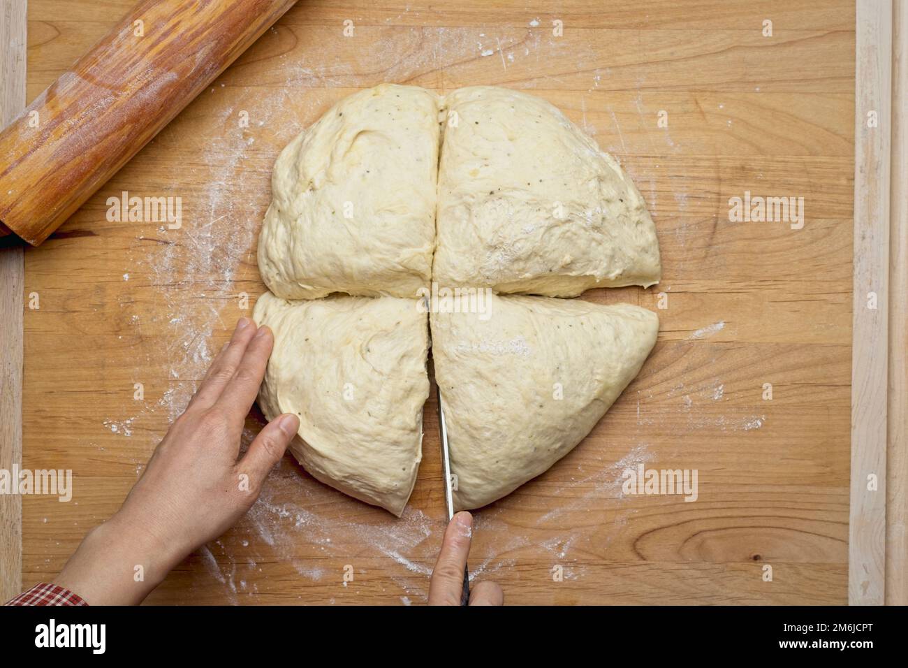 A Flatlay Photo Of A Ball Of Dough Being Cut Up On A Large Wooden A flatlay photo of a ball of dough being cut up on a large wooden