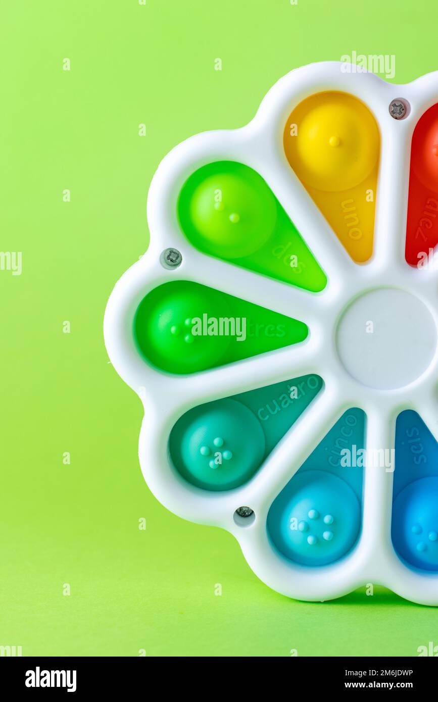 Presses with a finger anti-stress toy pop it on the green background. Colorful silicone poppit toy, bubble fidget, simple-dimple Stock Photo