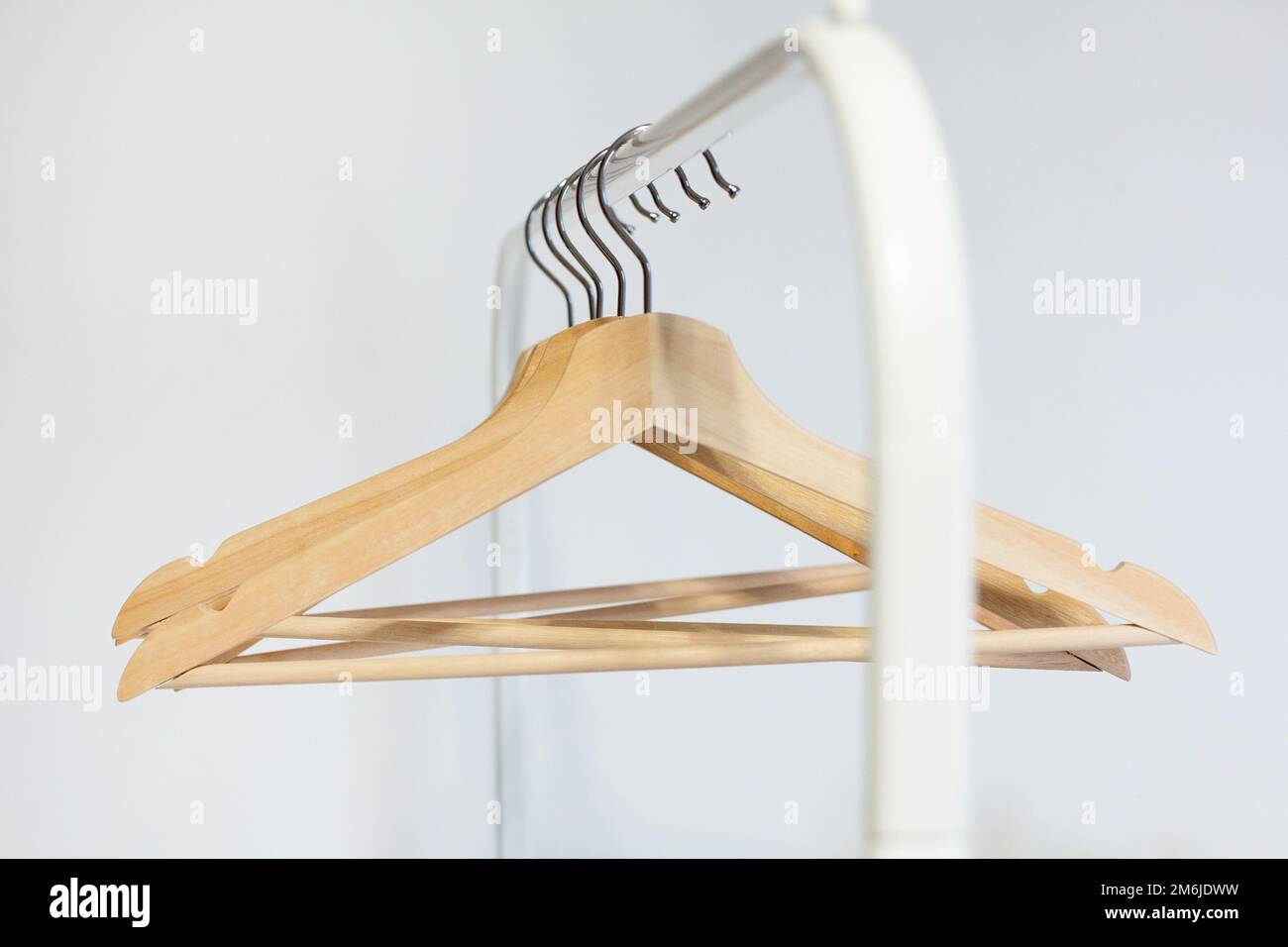 A wooden hanger hangs on a stainless steel rail in a room with white walls Stock Photo