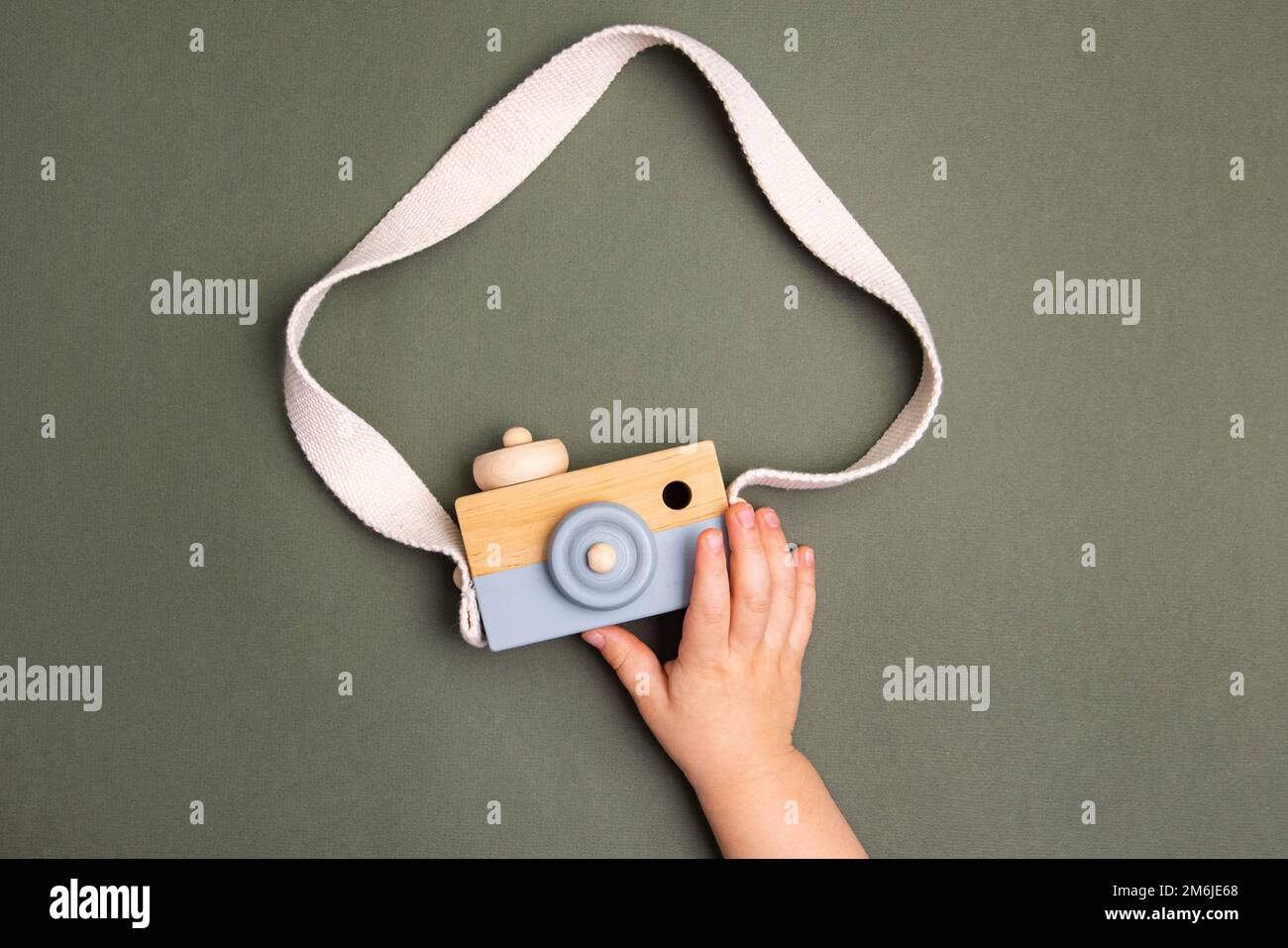 The boy play with wooden photo camera. Toy pastel color made of wood. Educational eco toys Stock Photo