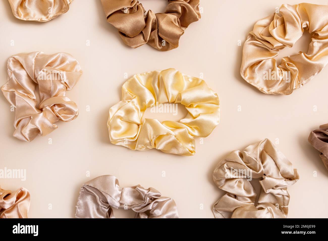 Collection of trendy silk elastic bands scrunchies on beige background. Diy accessories and hairstyles concept, luxury color Stock Photo