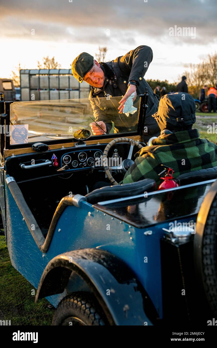 Male wiping clean the front wind screen of an open top pre war austin 7 car with a clean cloth before the Dave Wilcox Memorial hill trials. Stock Photo
