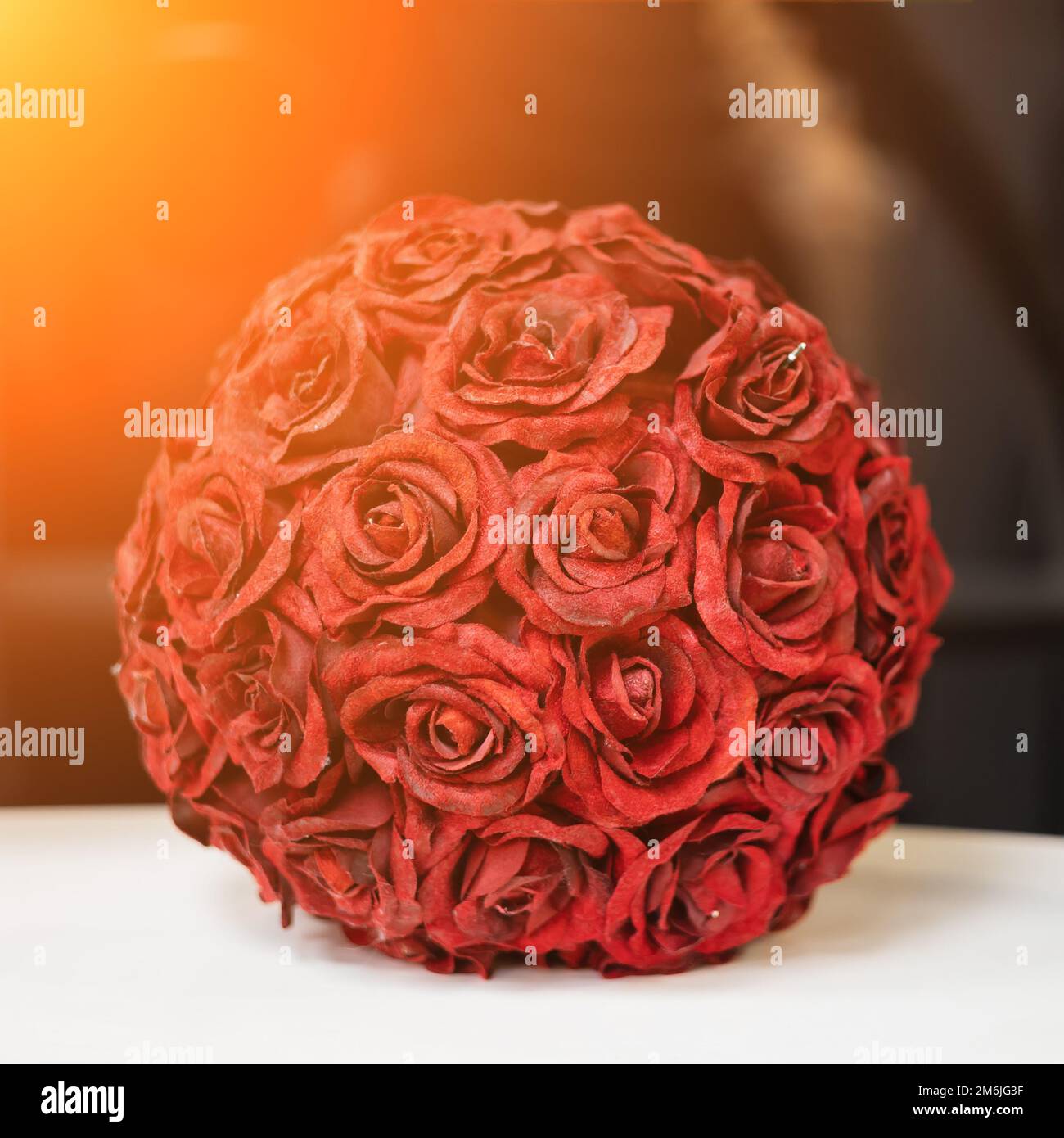 A decorative ball of red rose sepals stands on a white surface in the interior. Soft focus. Stock Photo