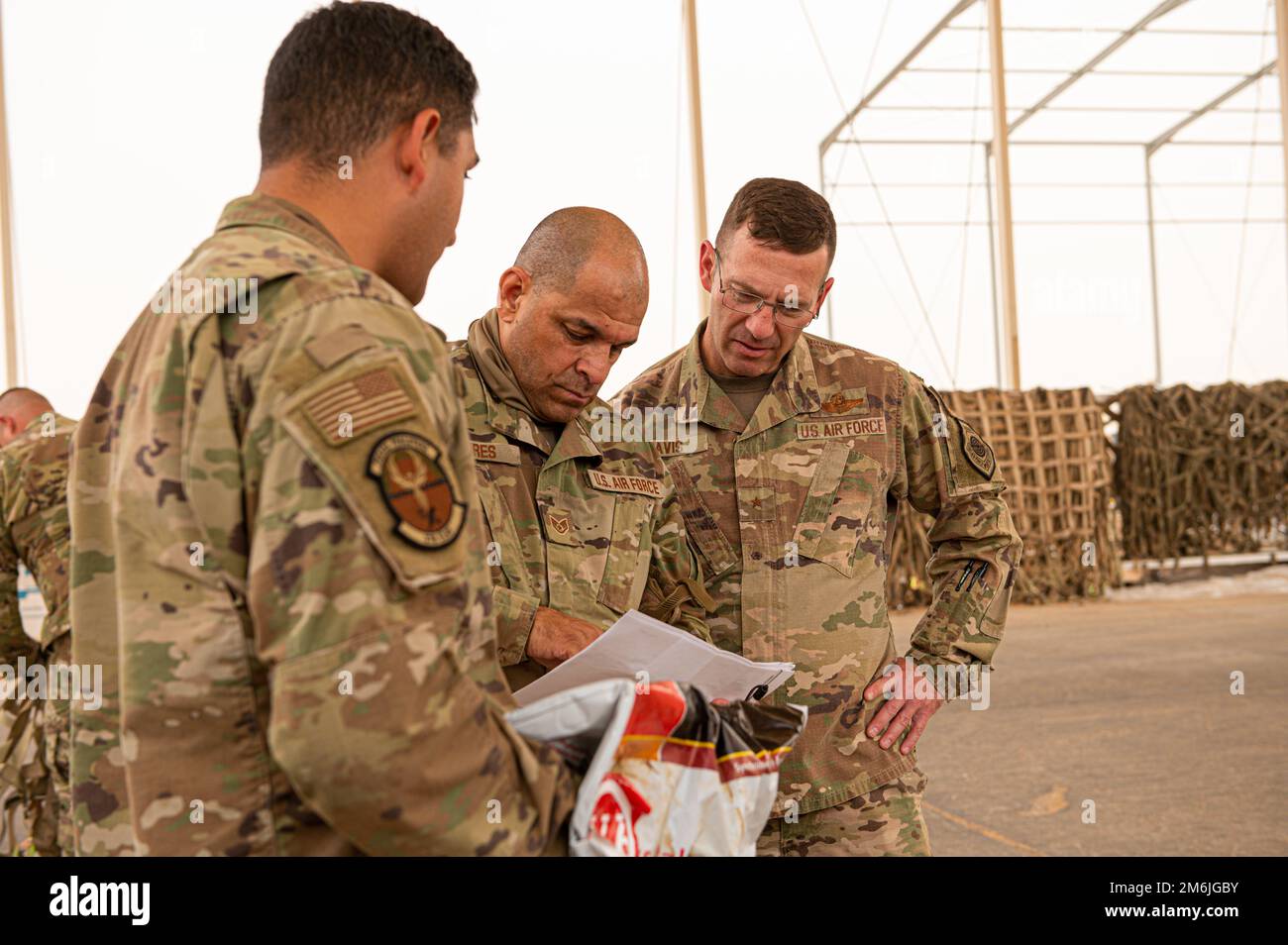 U.S. Air Force Brig. Gen. Robert Davis, right, commander of the 378th Air Expeditionary Wing, learns how to process incoming cargo from Staff Sgt. Enrique Flores, a passenger operation representative with the Air Terminal Operations Center, during a “Roll Up Sleeves” visit with Airmen of the 378th Expeditionary Logistics Readiness Squadron, at Prince Sultan Air Base, Kingdom of Saudi Arabia, April 28, 2022. Davis and Chief Master Sgt. Jackson Helzer, command chief of the 378th AEW, regularly visit Airmen under their command, to experience first-hand their job and to share recognition of how ea Stock Photo