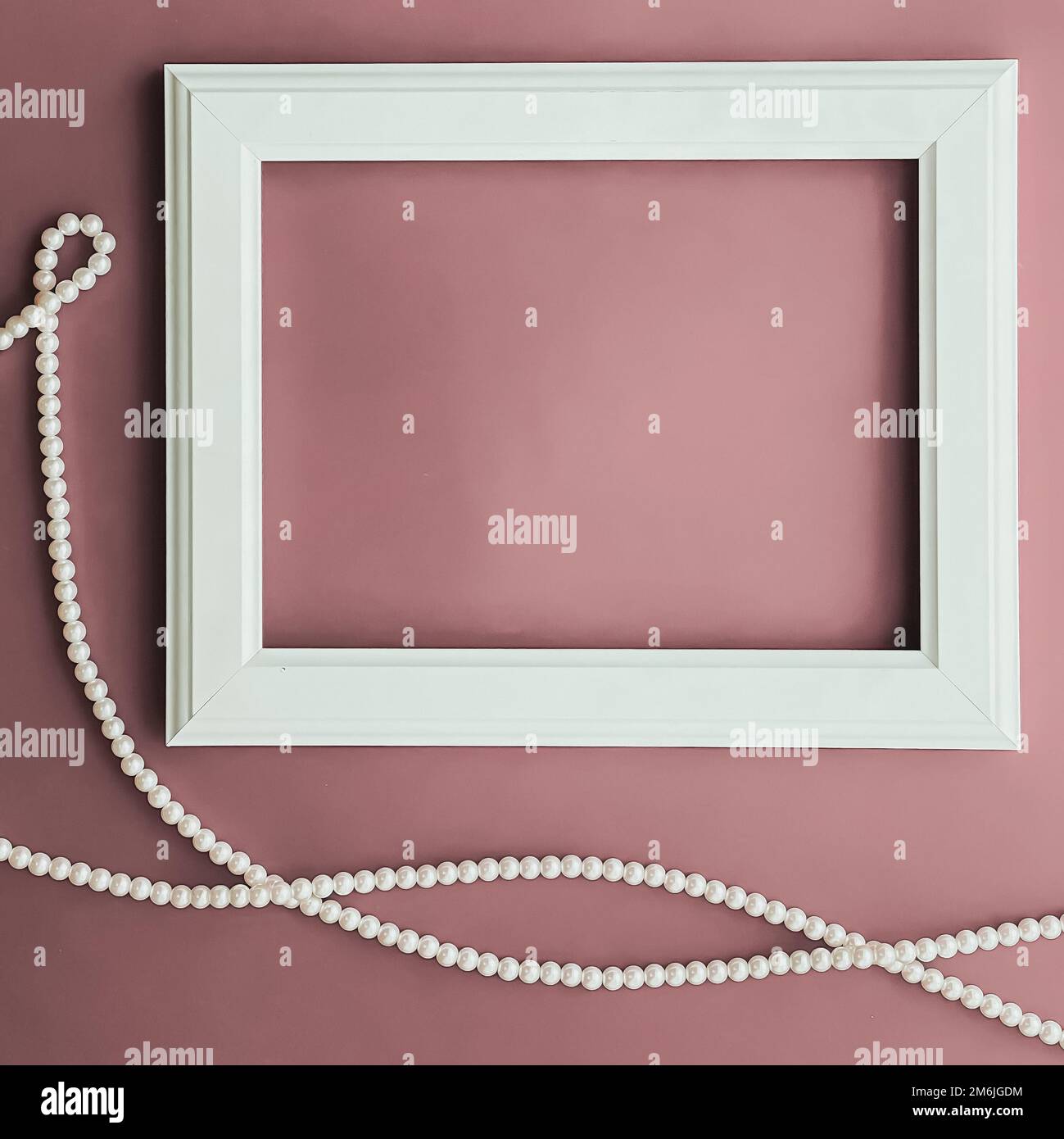 Horizontal art frame and pearl jewellery on blush pink background as