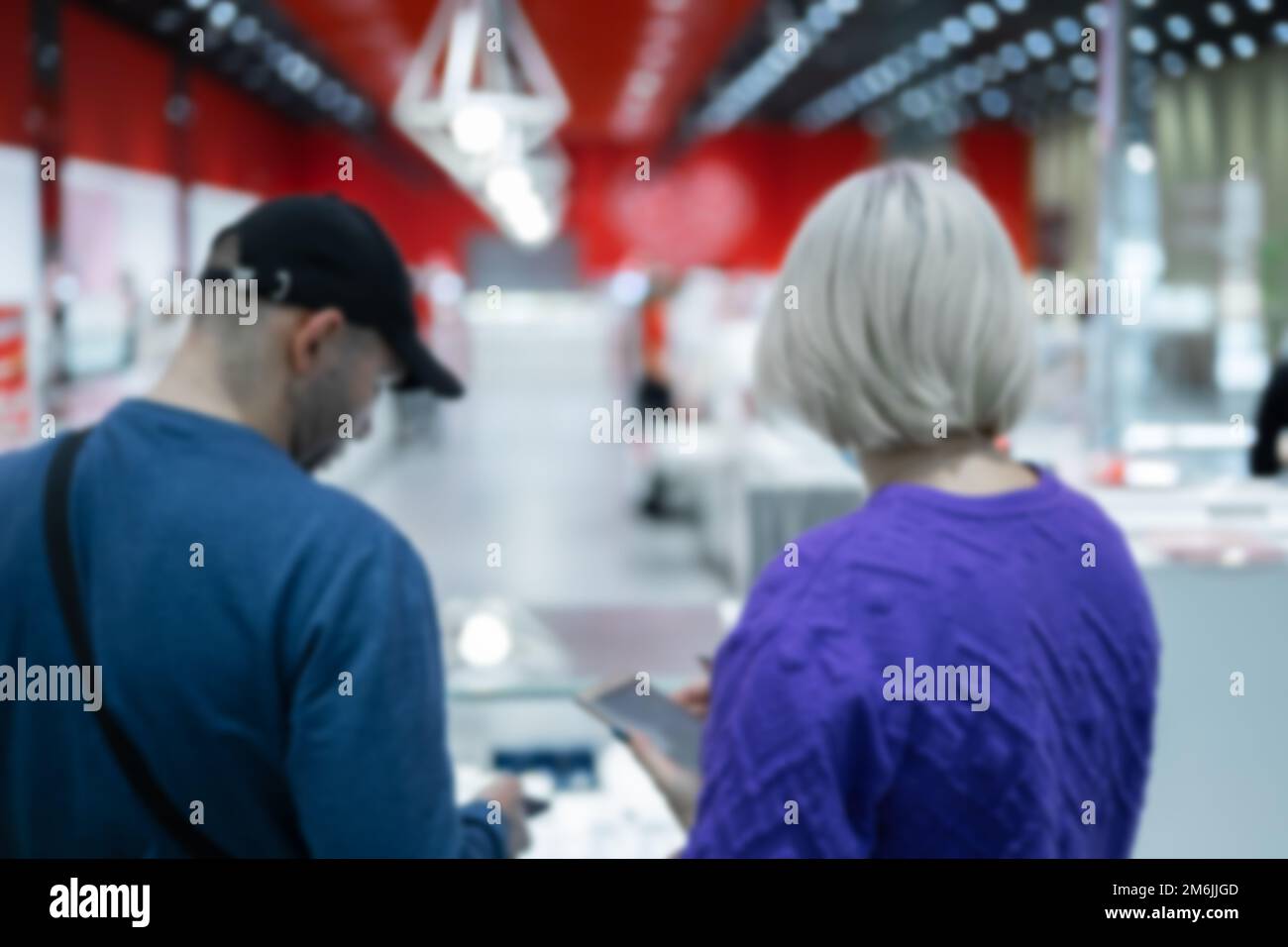 A man and a woman choose something in a jewelry store with a red and white interior. Defocused photo Stock Photo