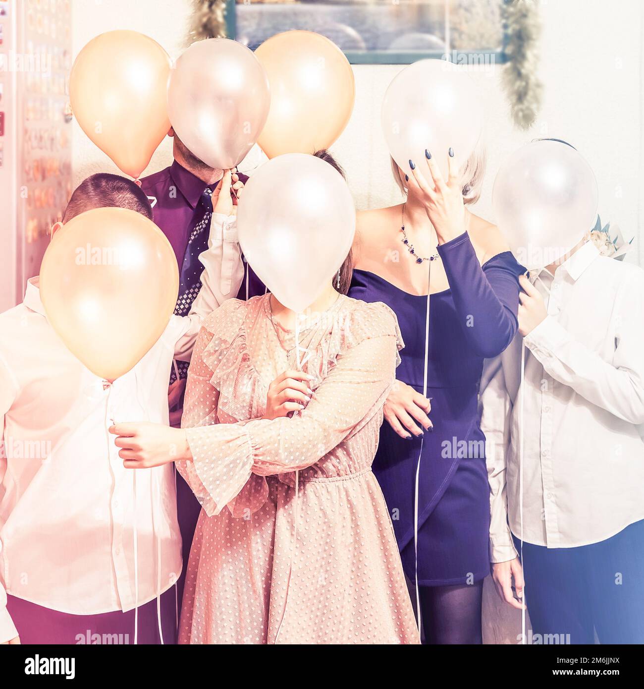 A family hiding their faces behind balloons. Cheerful holiday family photo. Stock Photo