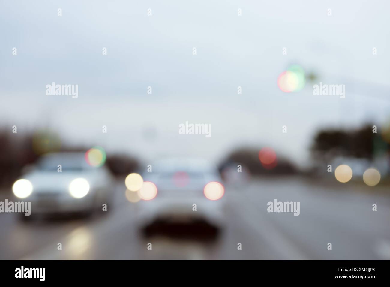 Cars with headlights on are driving down the road on a cloudy day. Blurred photo Stock Photo