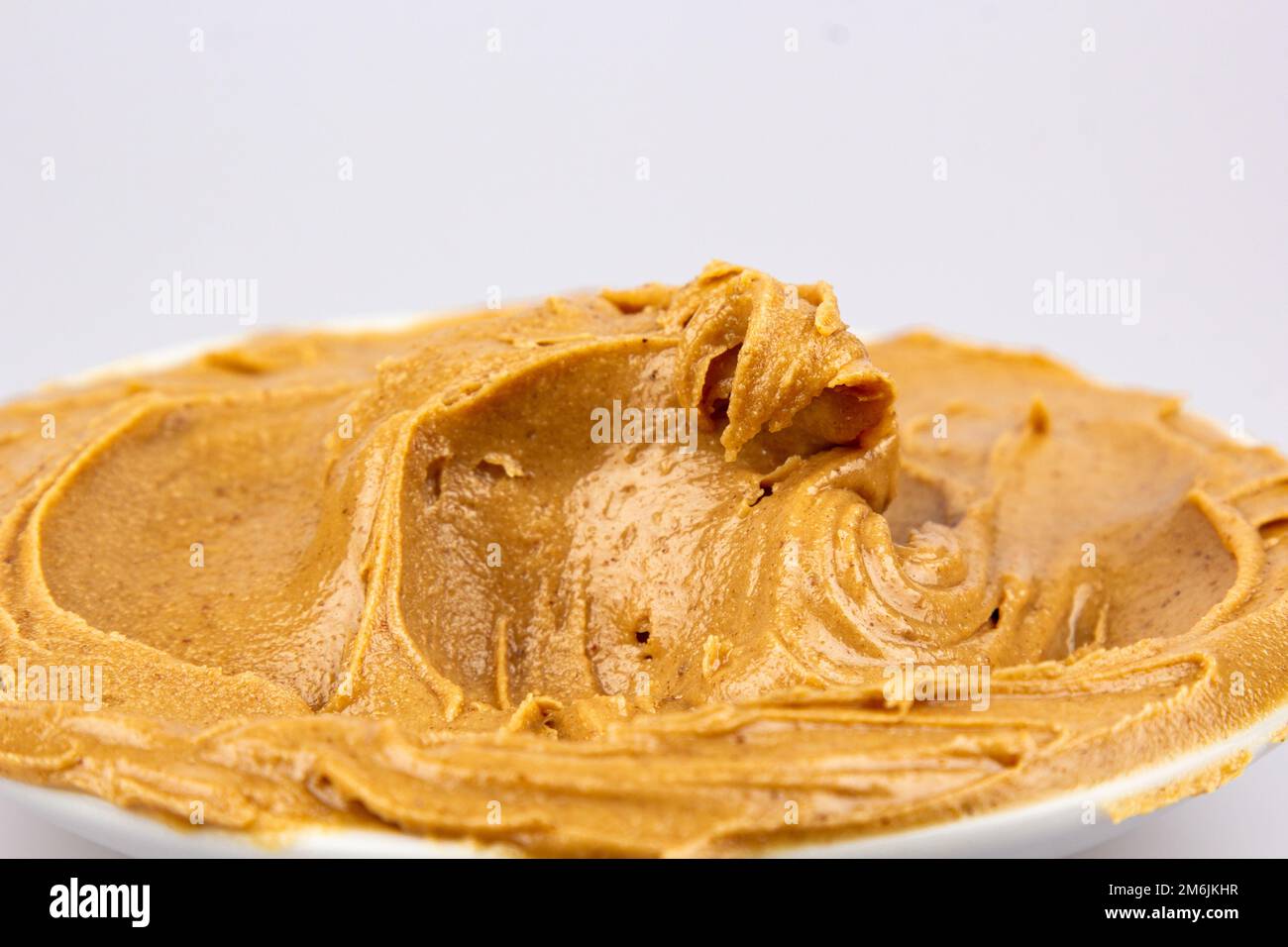 Peanut butter texture background. Creamy smooth brown walnut swirl close up. Delicious dark