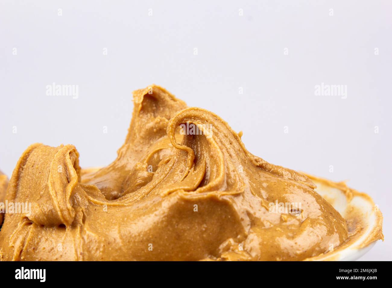 Peanut butter texture background. Creamy smooth brown walnut swirl close up. Delicious dark