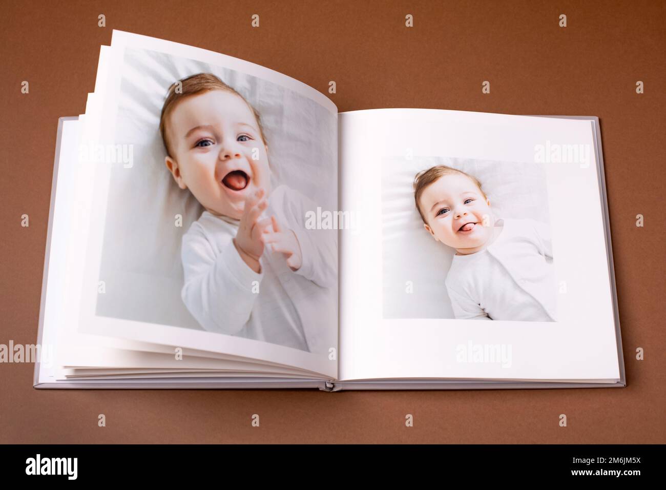 Baby's photo book on brown background . Children's emotional portrait.Cute toddler boy Stock Photo