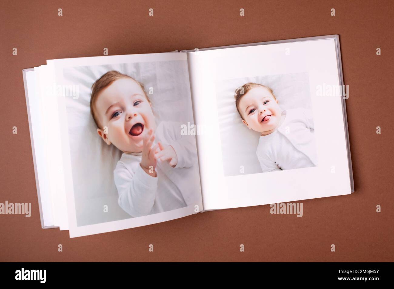 Baby's photo book on brown background . Children's emotional portrait.Cute toddler boy Stock Photo
