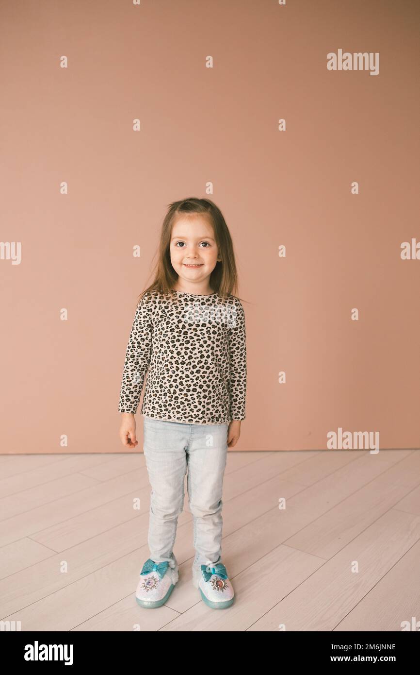 Small girl smiling against pink wall wearing a cheetah shirt Stock Photo