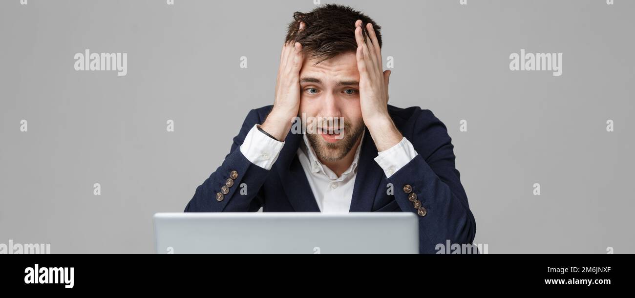 Business Concept - Portrait handsome stressful business man in suit shock looking at work in laptop. White Background. Stock Photo